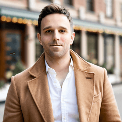 Andrew Baldwin in a camel coat on a city street