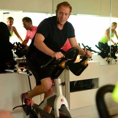 Danny Orlick riding a spin bike in a group fitness studio