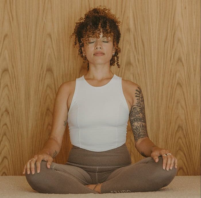 A barre3 instructor sitting cross-legged with her eyes closed