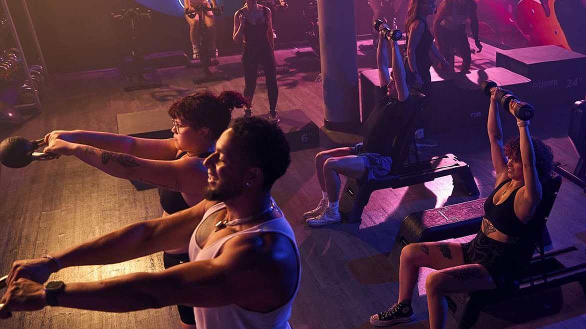 An EōS Fitness group fitness class working out under purple lights
