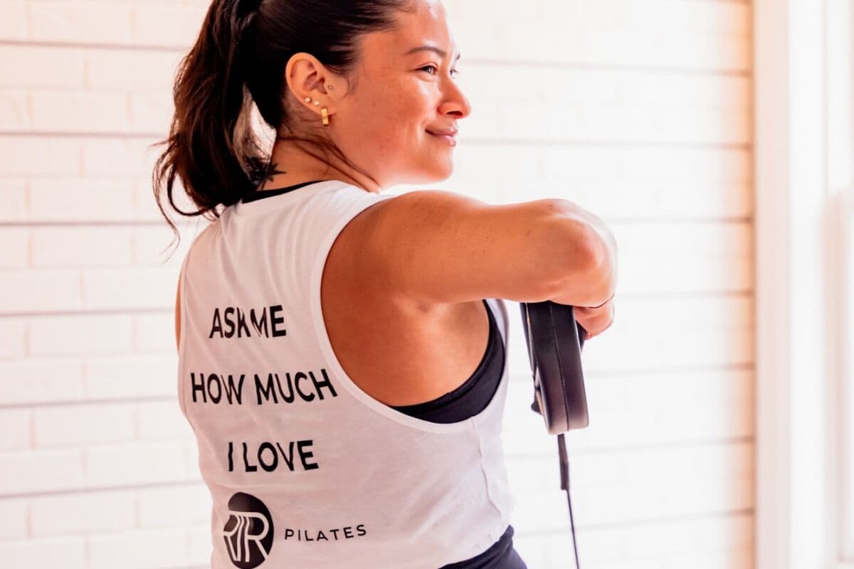 An RTR Pilates instructor in an “Ask me how much I love RTR Pilates” tank top